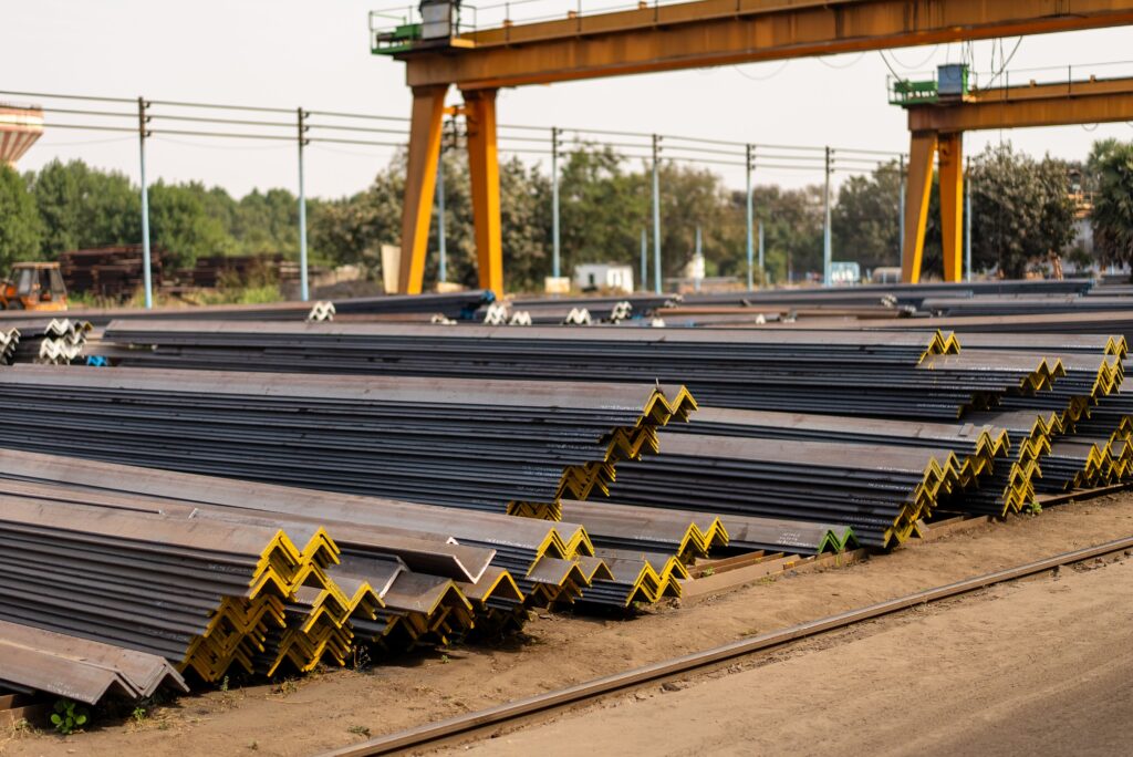 Numerous steel beams neatly stacked in an industrial yard during daytime.